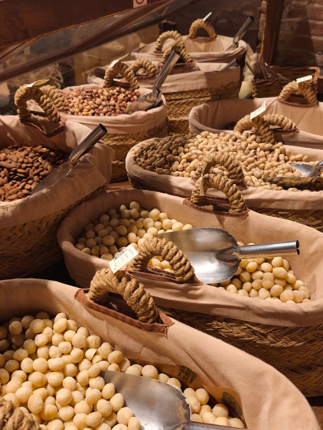 Cestas de frutos secos y legumbres con cucharones de madera en una tienda