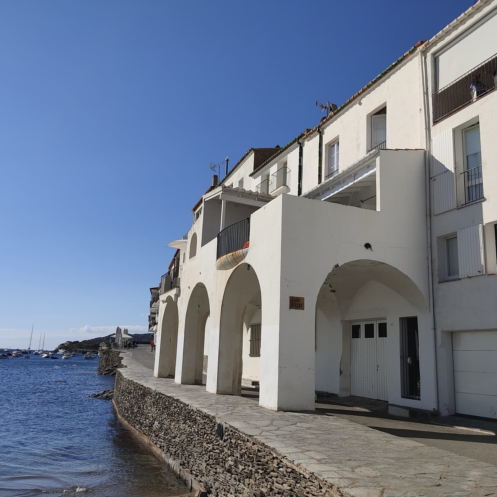 Whitewashed seafront houses reflected in the calm water of a Costa Brava village