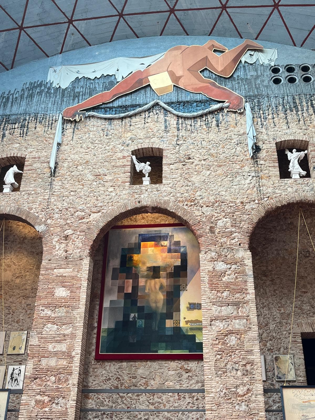 A courtyard wall of the Dalí Theatre-Museum hung with a large pixelated portrait