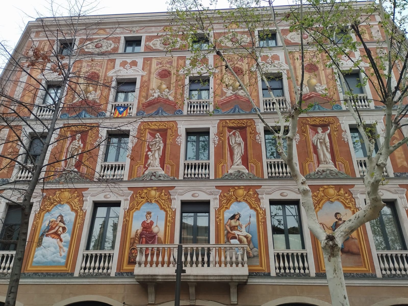 A Modernist Eixample façade painted with allegorical figures between the windows