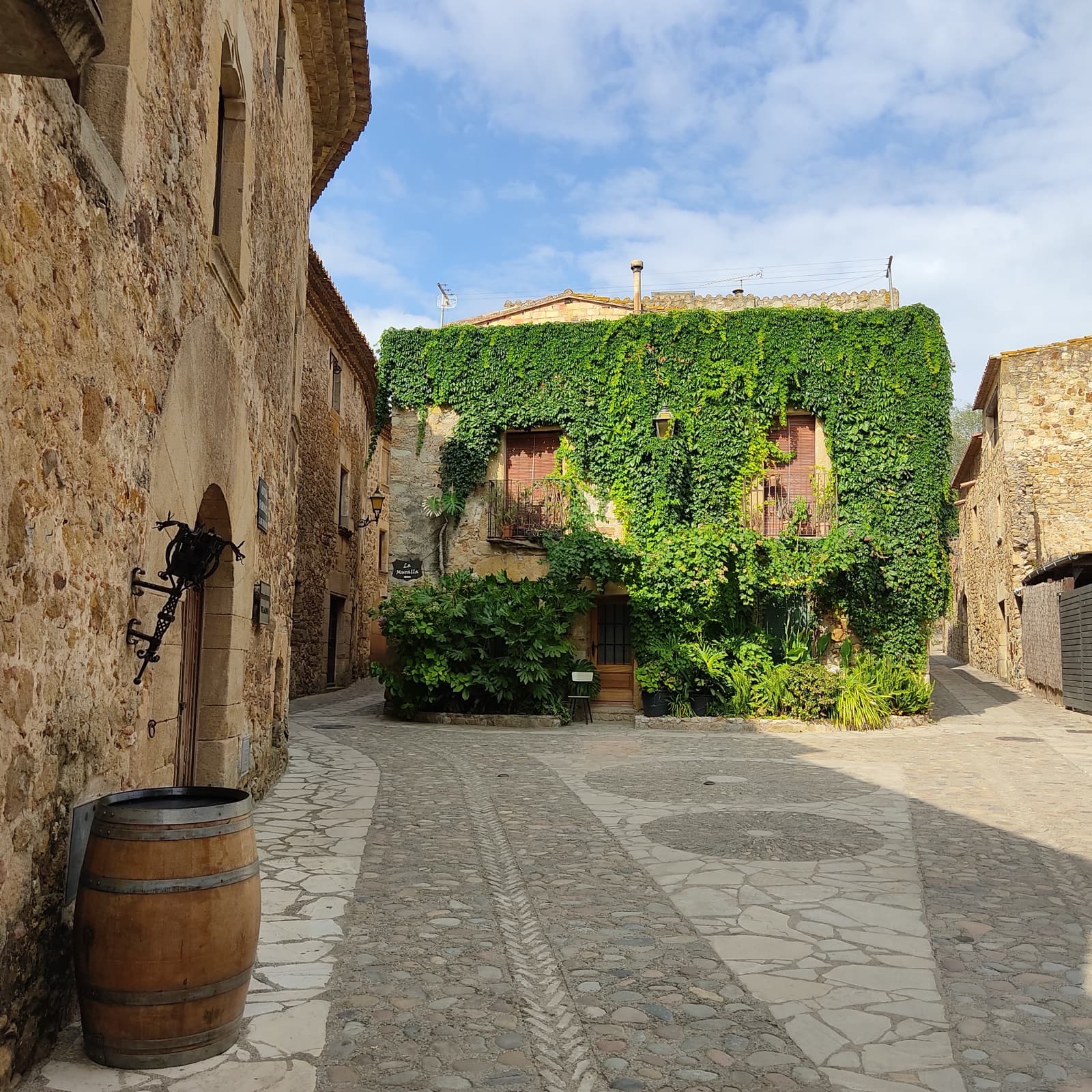 A cobbled square between golden-stone medieval houses in a Baix Empordà village