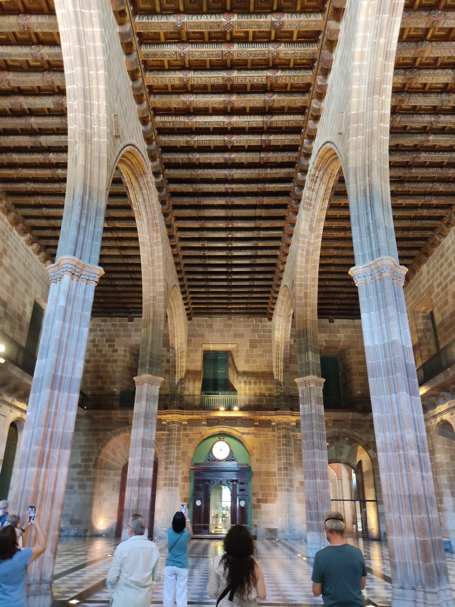 Visitors beneath the tall stone Gothic arches and columns of the medieval hall of the Llotja de Mar