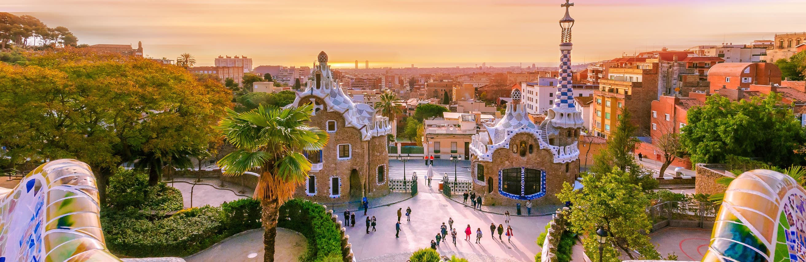 The fairy-tale pavilions at the entrance to Park Güell at sunset, with Barcelona and the sea beyond