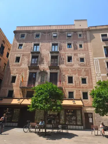 Un edificio de piedra frente a una pequeña plaza con árboles
