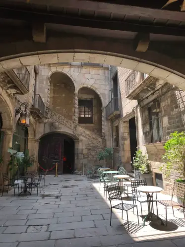 Mesas de café en un patio medieval de piedra apartado de la calle