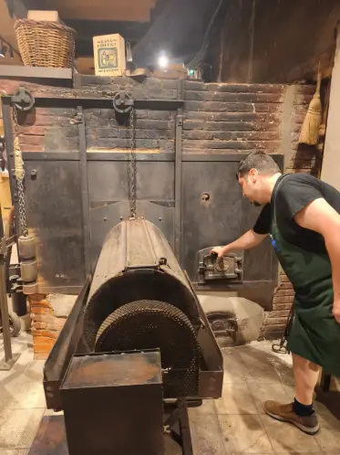 Un trabajador atendiendo el viejo horno de tostar de leña