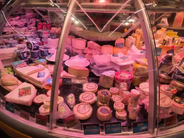 A curved case of cheeses and cured meats under the stall lights
