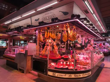 Cured hams hanging above the counter of a charcuterie stall