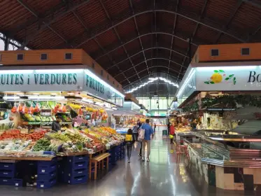 Shoppers along a market aisle beneath the roof trusses