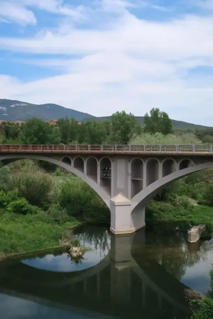 A tall arched bridge mirrored in the still water below