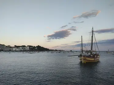 A wooden sailing boat at anchor as the light goes from the bay