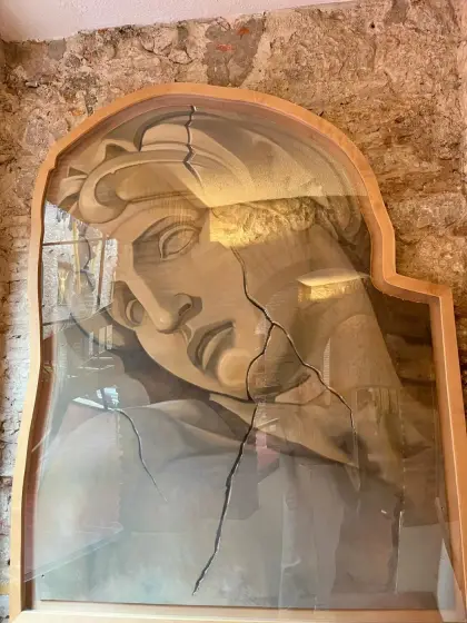 A monumental cracked stone face lit from within an alcove