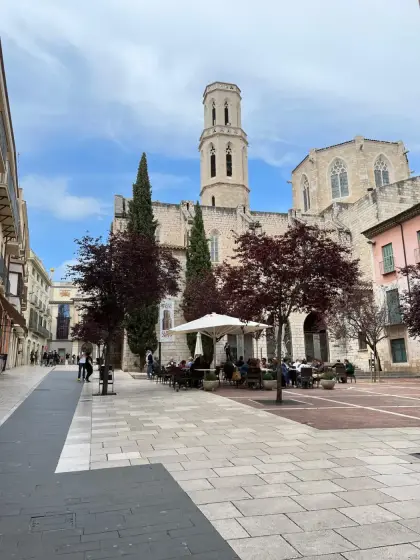A square in Figueres with café tables and the church tower beyond
