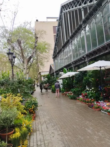 Puestos de flores junto a la marquesina de hierro del mercado del barrio