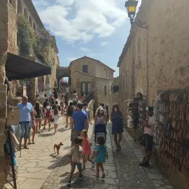 A busy village street with postcard stands and shopfronts