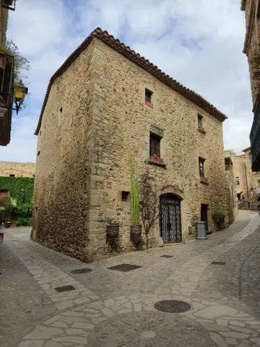 A tall stone house holding the corner where two lanes meet