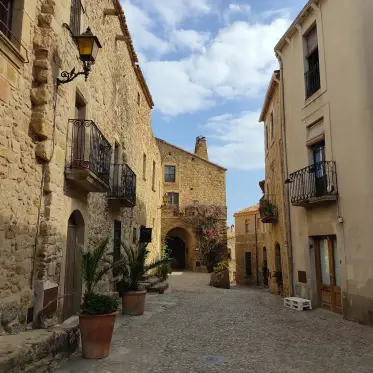A lane of balconied houses with potted plants at the doors