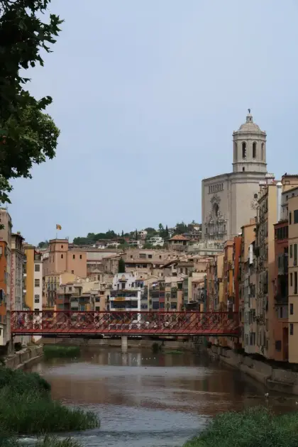 La pasarela roja de hierro sobre el Oñar, con la catedral y el campanario detrás