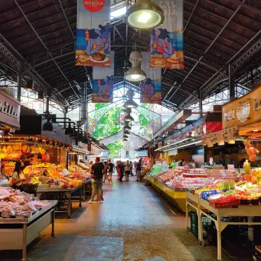 Produce and charcuterie stalls beneath the iron-and-glass roof of La Boqueria market