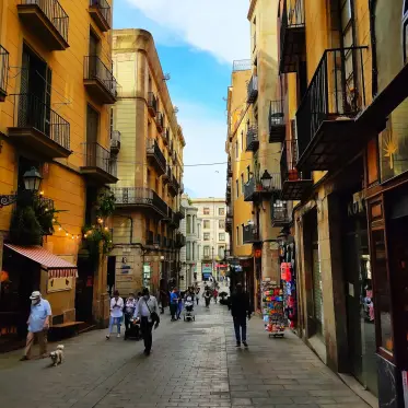 A busy Gothic Quarter lane lined with balconies, lanterns and shopfronts