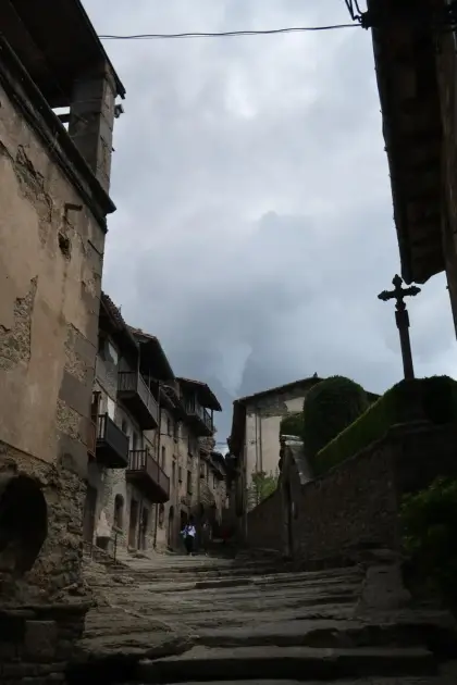 A steep stone street between tall houses under a heavy sky