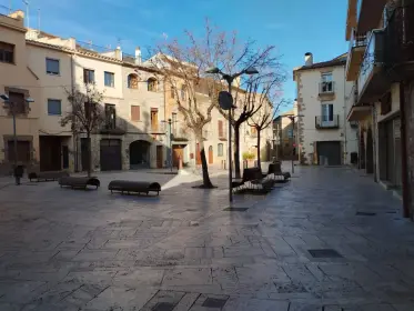 A wide paved square lined with townhouses and benches