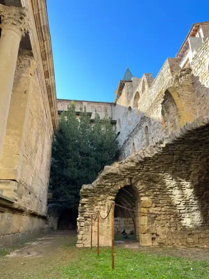 Ruined stone arches standing below a church on the rise
