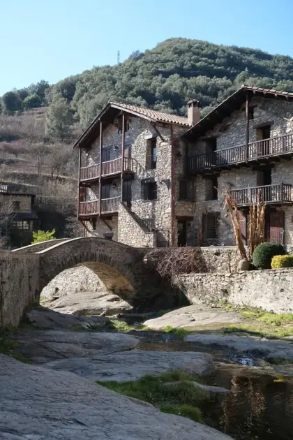 A stone bridge over the river below tall balconied houses