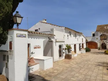 El patio encalado de una masía en activo, con un farol en el muro