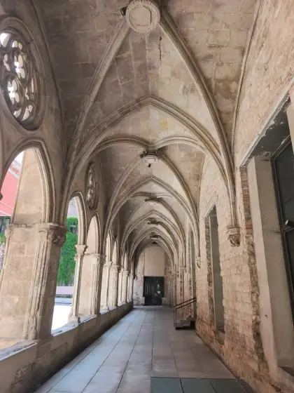 Una galería de claustro gótico, con las bóvedas de crucería abiertas al jardín
