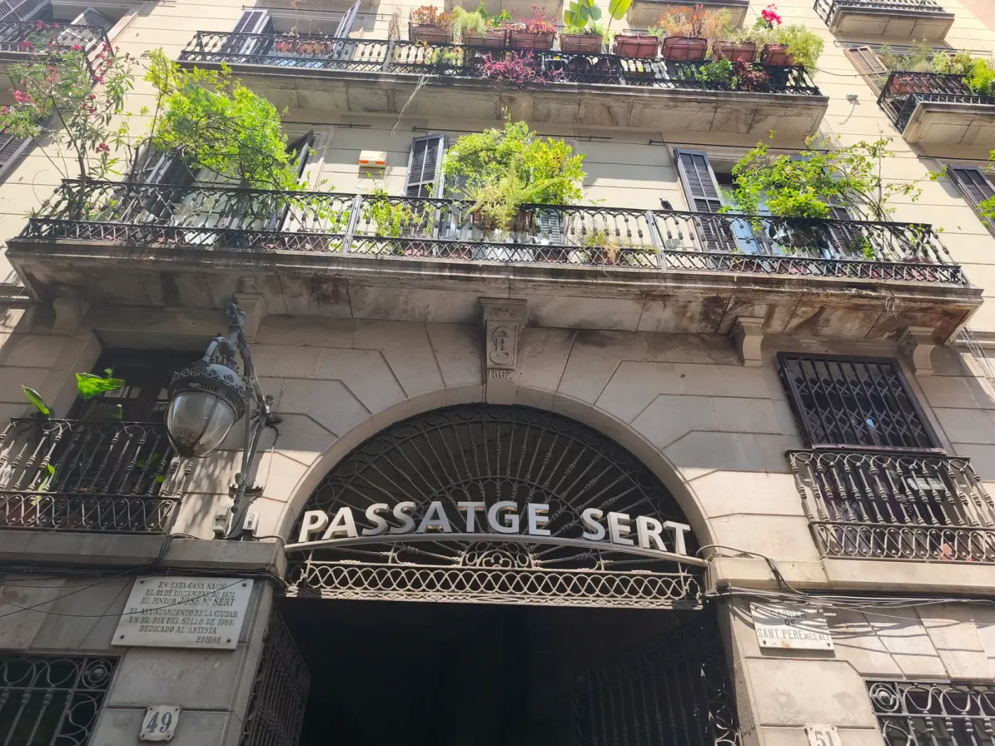 La entrada de hierro forjado del Passatge Sert, con los balcones cargados de plantas