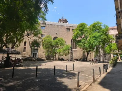 Una plaza sombreada de Sant Pere, con una iglesia de piedra cerrando un lado