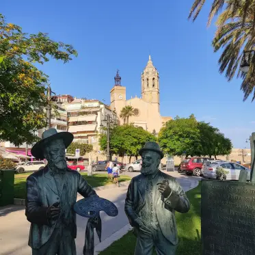Figures de bronze al passeig marítim amb el campanar al fons